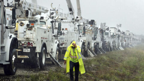 Charles Starling, a lineman with Team Fishel, is pelted with rain as he walks by a row of electrical line trucks stage in a field in The Villages, Florida, Thursday, September 26, 2024.