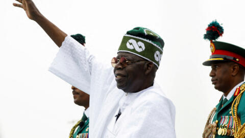 Nigerian President Bola Tinubu waves to a crowd as he takes the traditional ride in a ceremonial vehicle after his swearing-in ceremony in Abuja, Nigeria on May 29, 2023.