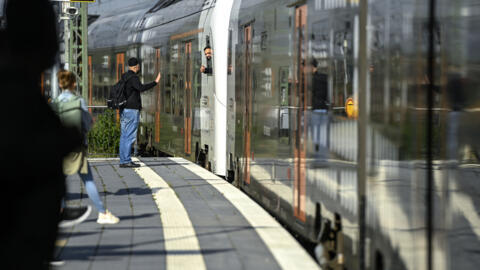 Travellers stand on a platform where a local train is arriving at the main railway station in Dortmund on June 1, 2022. 