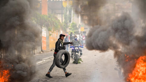 A protester burns tires during a demonstration calling for the resignation of Prime Minister Ariel Henry in Port-au-Prince on February 7, 2024.