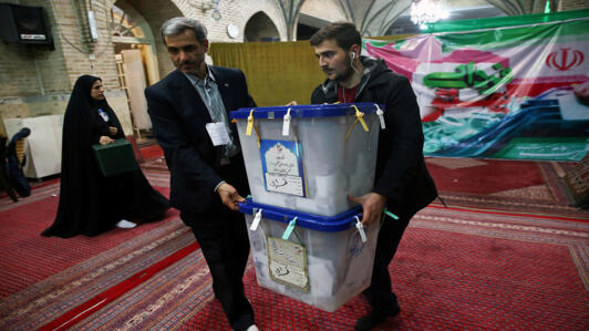 رجلان يحملان صندوقي انتخابات إيران البرلمانية