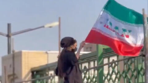 A female football fan on the fence outside of the Mashhad stadium.