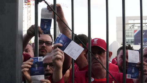 Liverpool fans show tickets in front of the Stade de France prior Saturday's Champions League final. Uefa says fake tickets led to delays in starting the match but the Enfield club says its fans were mistreated.