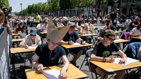 2023 年 6 月 4 日，在巴黎著名的香榭丽舍大道上，为打破“世界上最大听写”记录的参与者正在 等待听写开始，香榭丽舍大道变成了一个巨大的露天教室。