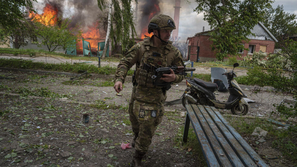 Un policier court devant une maison en feu détruite par une frappe aérienne russe à Vovchansk, en Ukraine, le 11 mai 2024.