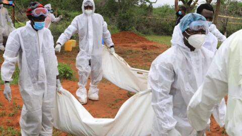 Forensic experts carry the bodies of suspected members of a religious cult.