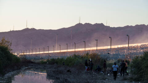 Migrantes caminham ao longo da fronteira entre os Estados Unidos e o México em um acampamento improvisado em El Paso, Texas, Estados Unidos, em 3 de abril de 2024.