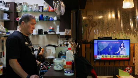 A person stands in a cafe as a news broadcast shows China announcing new military drills around Taiwan, in  Taiwan, May 23, 2024.