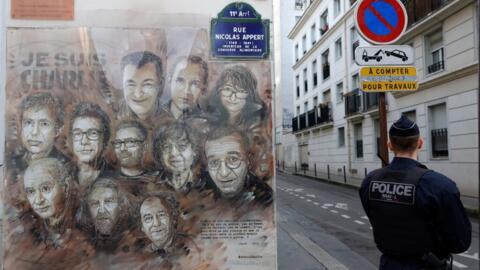 A police officer stands guard near a drawing depecting eleven of the victims ahead of a ceremony marking the eigth anniversary of the jihadist attack of the satirical magazine Charlie Hebdo that killed 12 people in Paris, on January 7, 2023. 