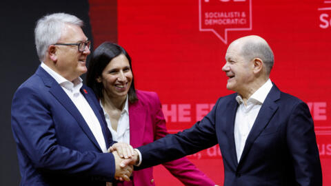 O chanceler alemão Olaf Scholz aperta a mão de Nicolas Schmit, ao lado da secretária do Partido Democrata, Elly Schlein, depois que Nicolas Schmit foi eleito candidato conjunto do Partido dos Socialistas Europeus (PES) para as eleições do Parlamento Europeu em junho de 2024, no dia do congresso eleitoral do PES em Roma, em 2 de março de 2024.
