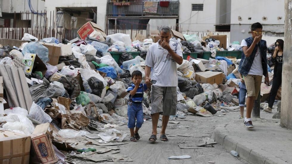 Des passants dans une rue de Beyrouth où les poubelles s'amoncellent, le 26 août 2015.