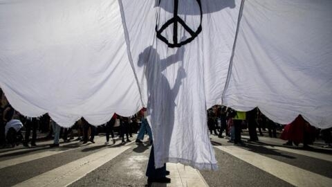 In this file photo, a woman holds a peace sign in Los Angeles. International activists are gathering in Paris this week to call for a commitment to resolve conflicts around the world.