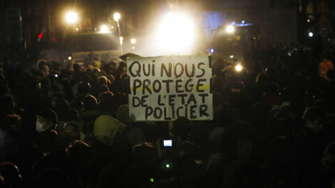 "Quem nos protege do estado policial", diz o cartaz mostrado durante um protesto contra um projeto de lei sobre imagens policiais, em Paris, sábado, 21 de novembro de 2020. Milhares de pessoas saíram às ruas em Paris e em outras cidades francesas no sábado para protestar contra uma proposta de lei de segurança que, segundo eles, iria afetar a liberdade de informação e os direitos da mídia.