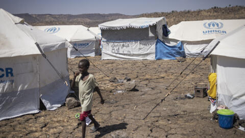 A child walks past a closed makeshift shop in the newly established Awulala refugee camp, near Maganan, 80 km from the Sudanese border in Ethiopia's Amhara region, on February 28, 2024. Having escaped a raging war at home, Sudanese refugees in Ethiopia face more conflict and insecurity as the border region of Amhara is plagued by unrest and clashes that sees the Ethiopian National Defense Force battling an ethnic Amhara militia known as 'Fano'. According to United Nations High Commissioner for Refugees (UNHCR) over 100,000 people have crossed into Ethiopia from Sudan since April 2023. Sudanese and other refugees in the border camps in Amhara lament a lack of security, difficult communication with the outside world - the Ethiopian government has disrupted access to mobile internet in the region since August 2023 - and a general sense of abandonment, raising the question if they fled a dire situation to end up in similar one. (Photo by Michele Spatari / AFP)