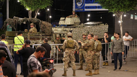 Members of Lebanese Army stand as people gather near the site of an Israeli strike in Beirut's southern suburbs on 23 September, 2024.