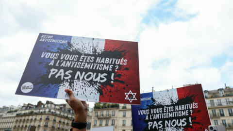 Protesters hold placards reading "You're used to antisemitism? Not us", at a rally against discrimination in Paris on 19 June 2024.