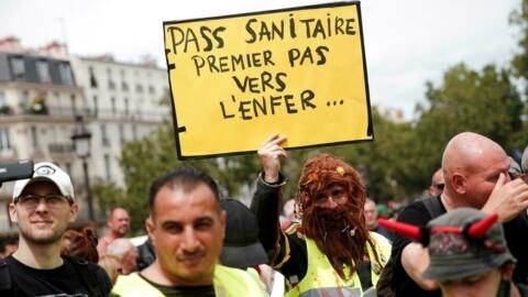 A protester holds a placard reading "Health pass first step to hell..." during a demonstration against France's current and proposed Covid-19 health restrictions in Paris on July 24, 2021.