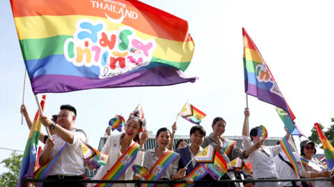 Miembros de la comunidad LGBT+ sostienen banderas en las que se lee "Igualdad en el matrimonio, el amor gana" en Bangkok el 18 de junio de 2024.