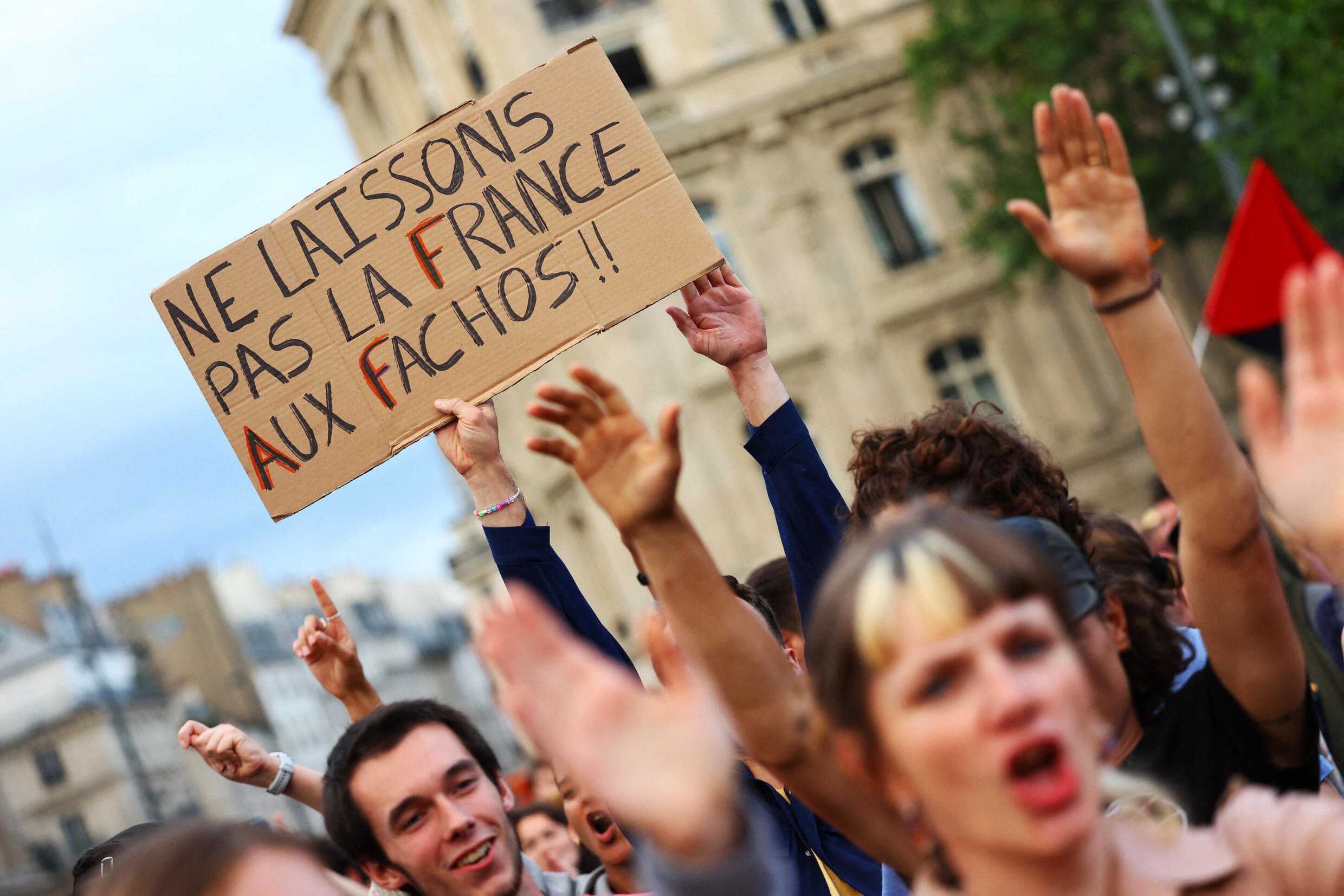 People gather in Paris to protest against the National Rally after it came top in the first round of parliamentary elections on 30 June 2024. The sign reads: "Don't leave France to fascists."