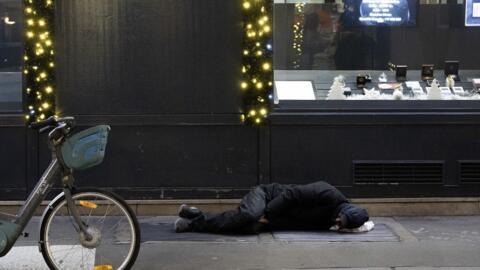 A homeless person lies over a heating duct in central Paris, on 8 January, 2024.