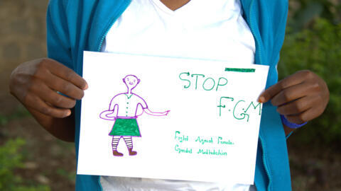 A young girl holds up a picture urging the end to the practice of FGM.