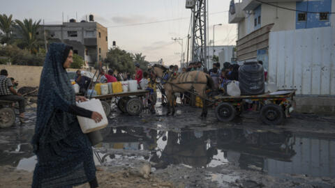 Palestinos enchem jarros de água perto de uma das poucas usinas de dessalinização em funcionamento em Gaza, em Deir al-Balah.