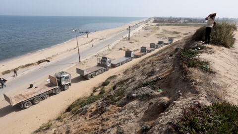 2024 年 5 月 18 日从加沙地带中部看到的卡车排队驶向美国建造的码头，在那里装载援助物资。