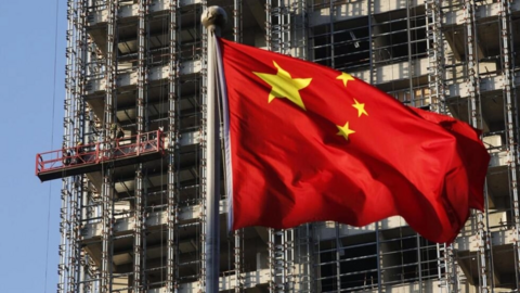 Le drapeau chinois flotte devant un immeuble en construction. La Chine traverse une période de crise immobilière aigue