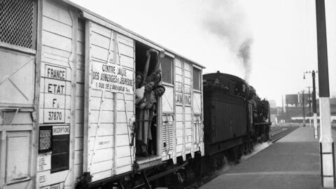 Women wave from a train wagon converted into a youth hostel in August 1933, three years before the introduction of paid holiday in France helped spur hundreds of thousands of people to travel.