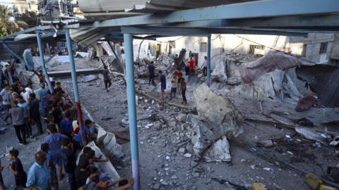 Palestinos observan las ruinas de una escuela de la ONU en el campo de refugiados de Nuseirat, en la Franja de Gaza, destruida en un bombardeo israelí.