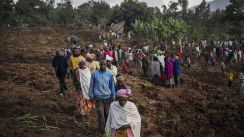 Decenas de habitantes y voluntarios abandonan el lugar del corrimiento de tierras al caer la noche tras excavar en el lodo en busca de supervivientes y cadáveres, el 24 de julio de 2024 en Gofa, al sur de Etiopía