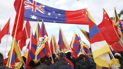 李强访澳，支持者和示威抗议者均举着旗帜和标语在议会外