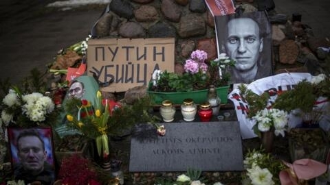 Photos of Alexei Navalny is seen among flowers and candles at the monument to the victims of soviet occupation in Vilnius, Lithuania, Saturday, Feb. 17, 2024. Poster with the words reading "Putin is a killer", left,. Russian authorities say that Alexei Navalny, the fiercest foe of Russian President Vladimir Putin who crusaded against official corruption and staged massive anti-Kremlin protests, died in prison. He was 47. (AP Photo/Mindaugas Kulbis)