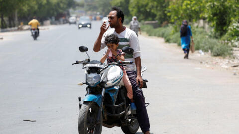 Um homem e uma criança bebem bebidas refrescantes oferecidas por moradores locais durante uma onda de calor em Narela, Nova Delhi, Índia, 29 de maio de 2024.