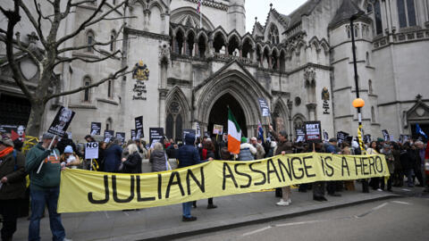 Manifestantes seguram cartazes enquanto protestam do lado de fora do Royal Courts of Justice, o Tribunal Superior da Grã-Bretanha, no centro de Londres, em 20 de fevereiro de 2024, enquanto o tribunal superior ouve o recurso final do Reino Unido do fundador do WikiLeaks, Julian Assange, contra sua extradição para os EUA.