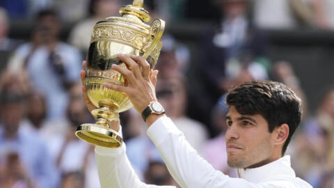 Carlos Alcaraz de España sostiene su trofeo en alto después de derrotar a Novak Djokovic de Serbia en la final individual masculina en los campeonatos de tenis de Wimbledon en Londres, domingo 14 de julio de 2024.