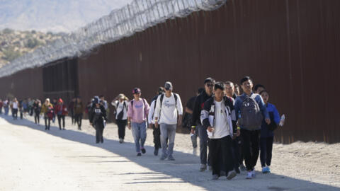 2023年10月24日，一群移民，其中许多人来自中国在穿越墨西哥边境寻求庇护后沿着边境墙行走，地点位于美国加州贾库姆巴附近。
