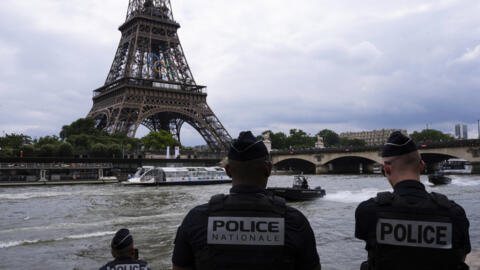 Police officers watch river police boats patroling past the Eiffel Tower, Tuesday, July 2, 2024 on the Seine river in Paris. The river will host the Paris 2024 Olympic Games opening ceremony on July 26 with boats for each national delegation. 