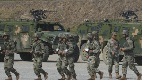 Chinese military personnel run in front of armored fighting vehicles during a participating in the Golden Dragon military exercise in Svay Chok village, Kampong Chhnang province, north of Phnom Penh C