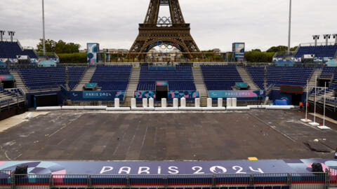 Workers work to convert the Eiffel Tower Stadium from the beach volleyball venue to the Paralympic blind football venue for the coming Paris 2024 Paralympic Games.