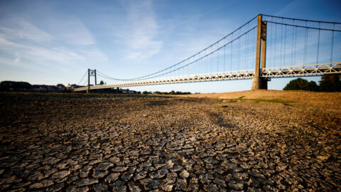 Cracked and dry earth is seen in the wide riverbed of the Loire River near the Anjou-Bretagne bridge as a heatwave hits Europe, in Ancenis-Saint-Gereon, France, June 13, 2022.