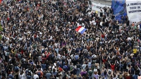 People wave national flags during an election night event following the first results of the second round of France's legislative election at Place de la Republique in Paris on Sunday.