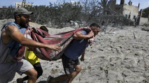 Palestinos evacuan a una persona muerta de un lugar alcanzado por un bombardeo israelí en Khan Younis, sur de la Franja de Gaza, sábado 13 de julio de 2024.