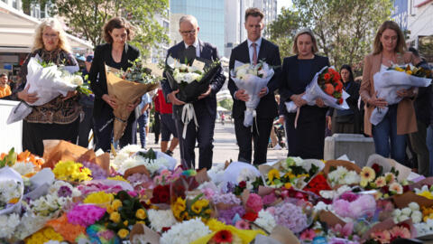O primeiro-ministro australiano, Anthony Albanese (quarto da esquerda para a direita), depositou flores neste domingo (14) em um memorial às vítimas perto do centro comercial Westfield Bondi Junction, em Sydney, palco de um ataque com faca na véspera.