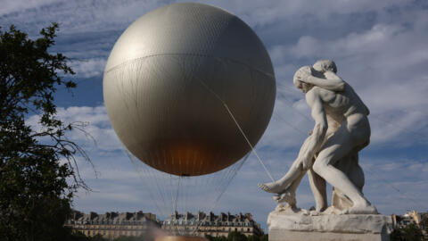 "The Good Samaritan", by François Sicard, pictured in front of the Olympic cauldron in the Tuileries Gardens. Tourism figures have risen significantly due to the Olympics and plans to keep the cauldron flying after the games are proving popular.