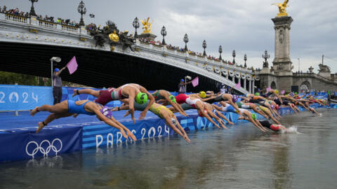 Atletas mergulham na água após largada da prova de triatlo individual feminino nos Jogos Olímpicos, em 31 de julho de 2024, em Paris, França.