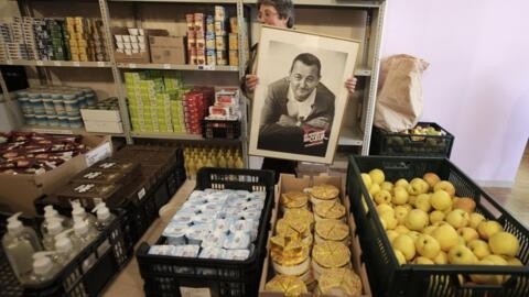 A portrait of French actor Coluche held by a volunteer of the charity he set up in 1985 to help French families in need, especially for food aid.