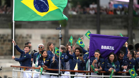 A jogadora de rúgbi Raquel Kochhann com a bandeira do Brasil  durante o desfile das delegações no rio Sena.