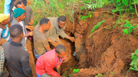 Moradores escavam para recuperar o corpo de uma vítima do deslizamento de terra de 22 de julho de 2024, após fortes chuvas, no sul da Etiópia.