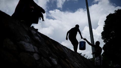 [Image d'illustration] Des personnes collectant l'eau d'un ruisseau d'eaux usées dans un camp de fortune où vivent des migrants au stade Cavani de Mamoudzou, sur l'île française de Mayotte, le 15 février 2024.